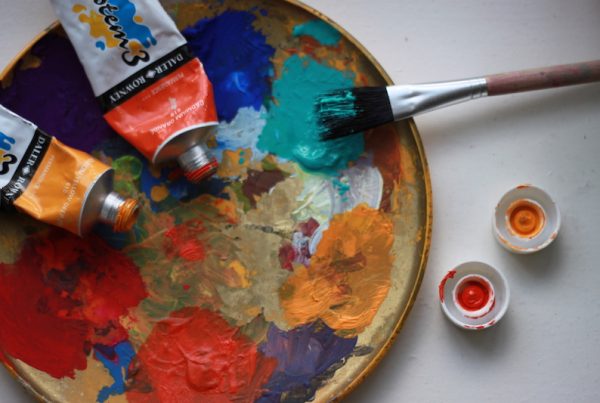 A paint pallet with paint tubes and a brush